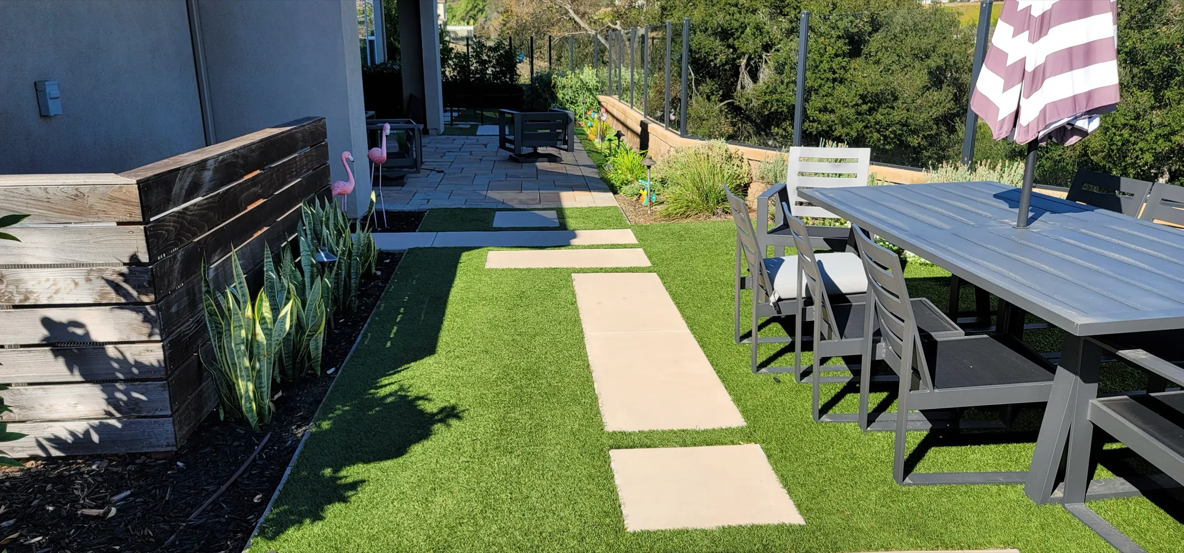 Artificial turf lawn with a planted and paved backyard edge